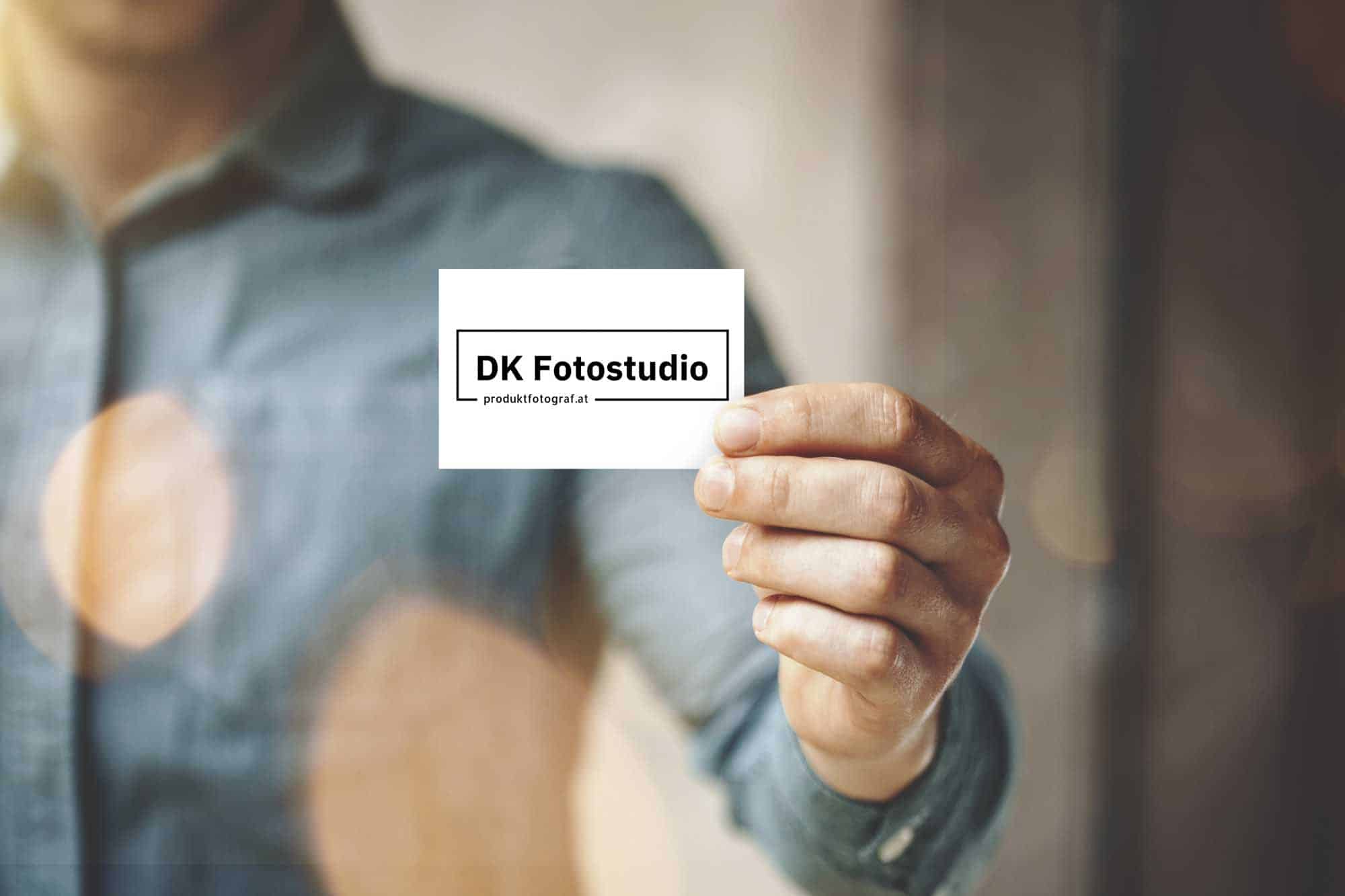 Mann hält eine Visitenkarte für DK Fotostudio Produktfotograf.at